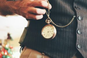 person holding round gold-colored pocket watch